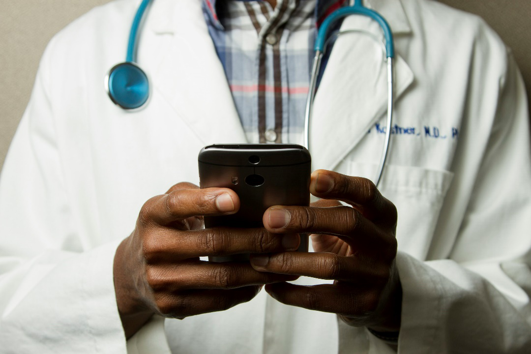 A doctor wearing a stethoscope using a smartphone