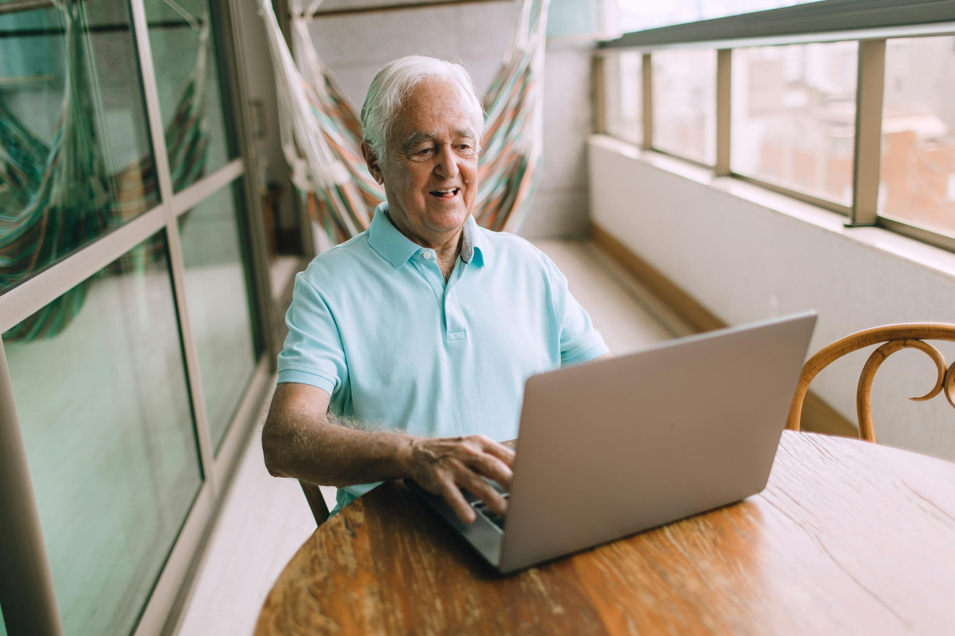 An elderly man reviewing his Medicare plan on a laptop at home.