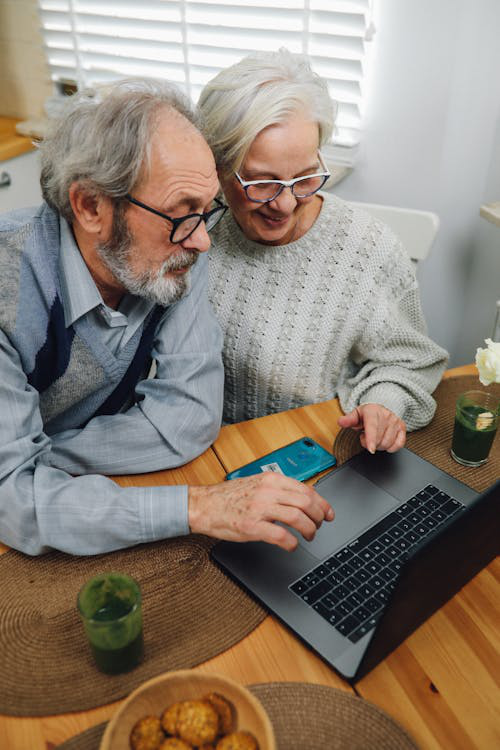 Senior couple looking at a laptop screen while discussing healthcare.