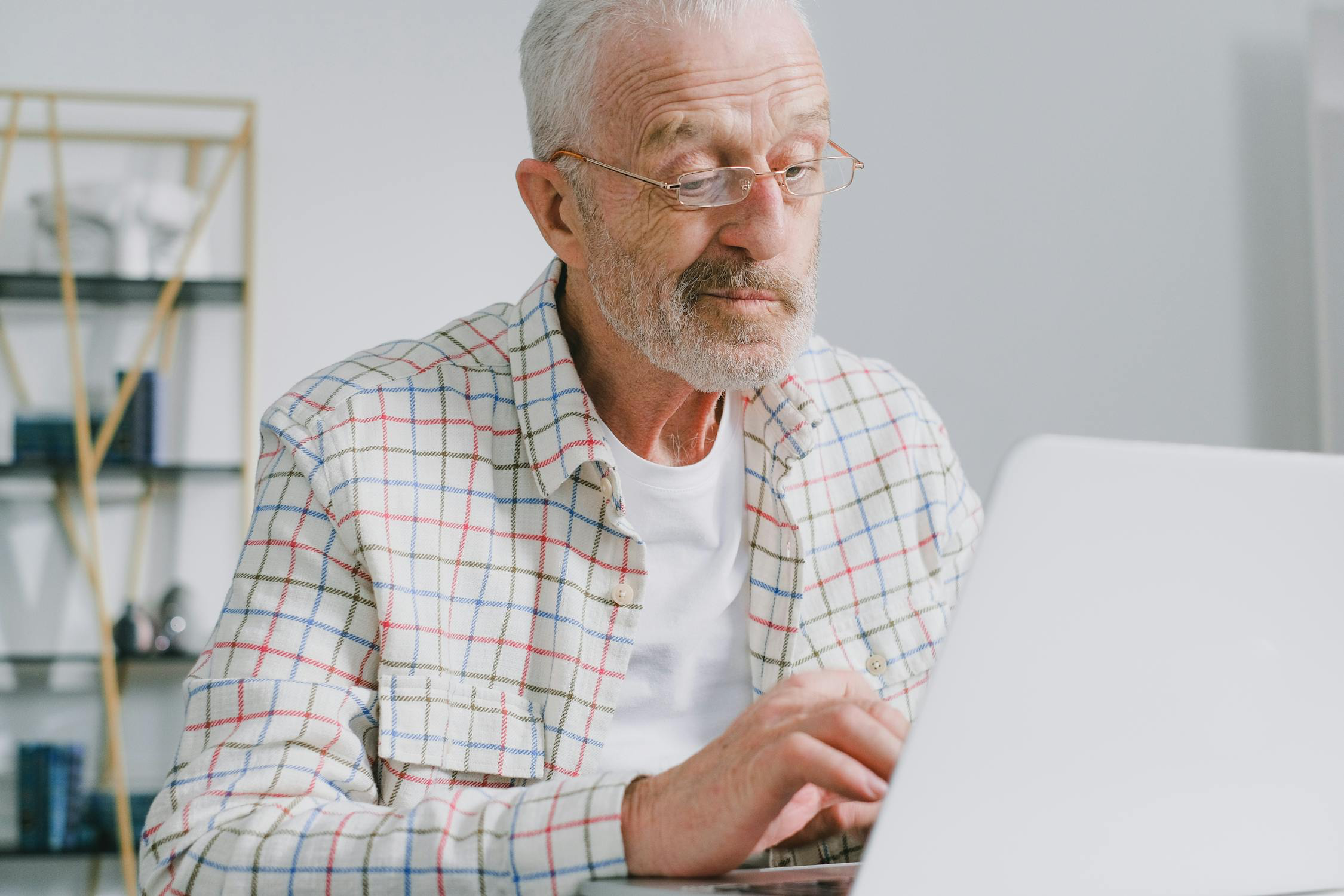 An elderly man thoughtfully reviewing documents at a desk.