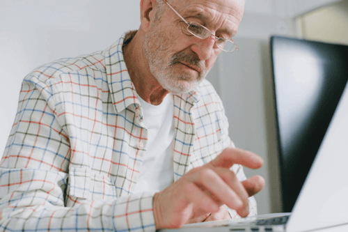 An elderly man researching Medicare options on his laptop.