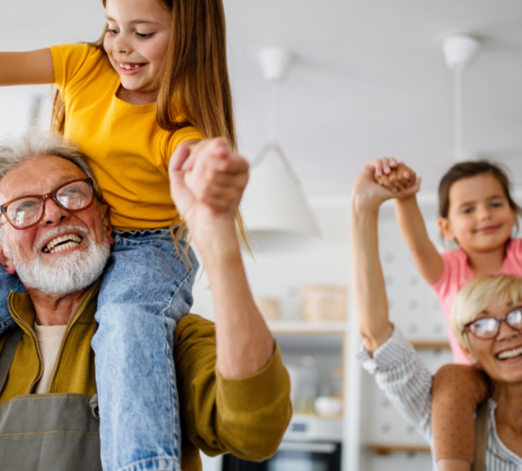 Grandparents playing with grandchildren in the kitchen.