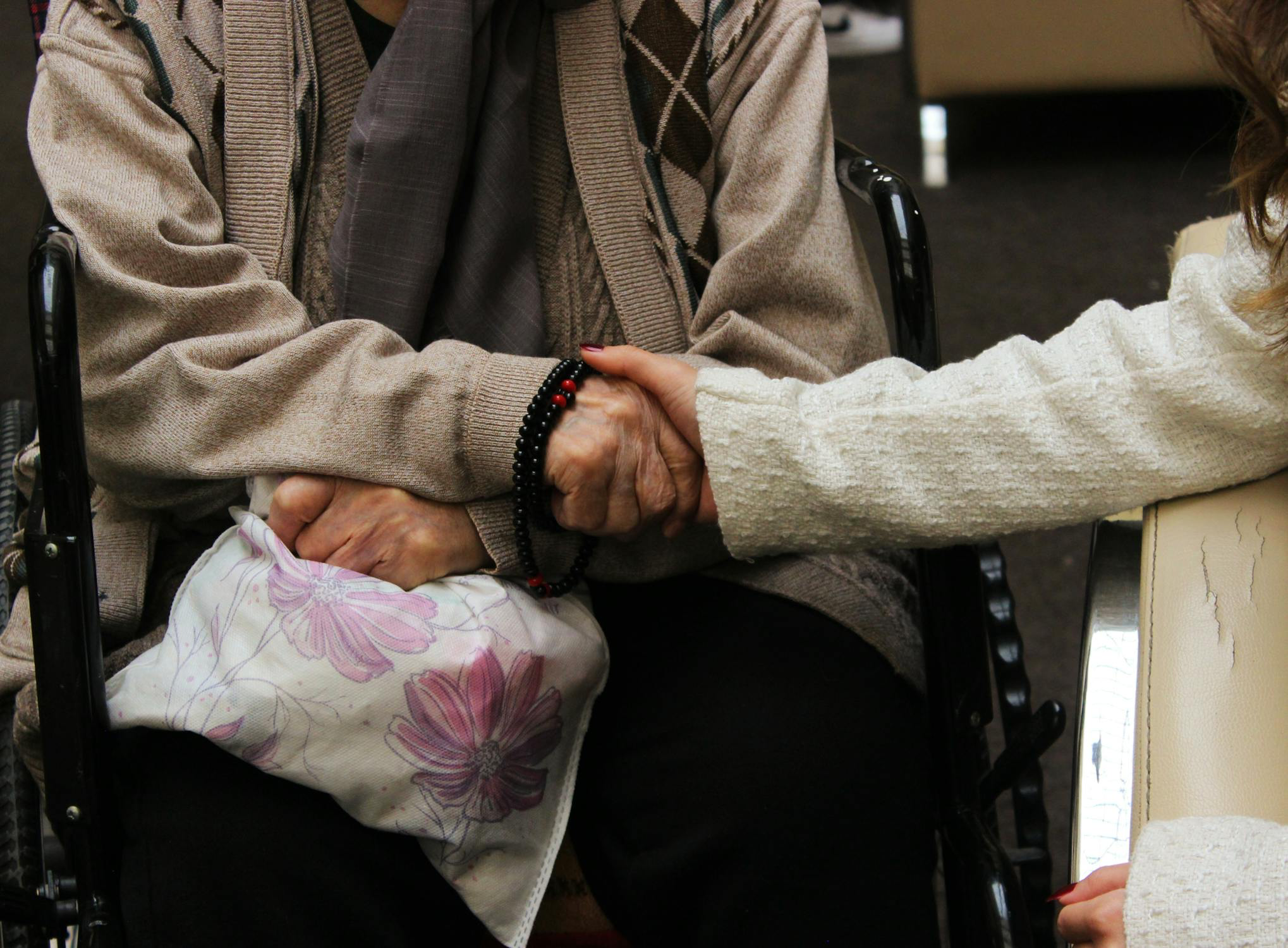 A woman holding her elderly parent's hand.